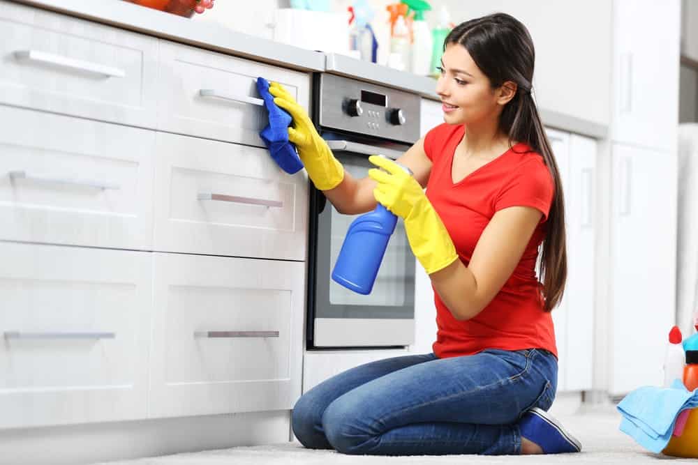 Woman is cleaning kitchen cabinets