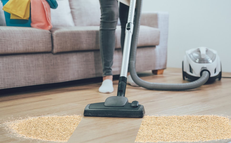 Person vacuuming sand in a living room
