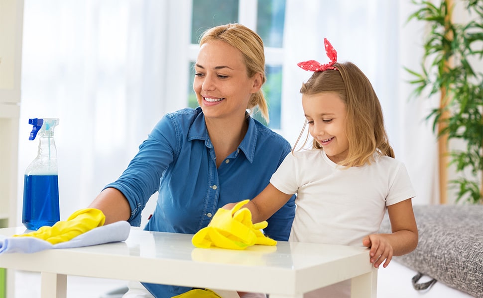 Mom and daughter smile while cleaning a kitchen counter