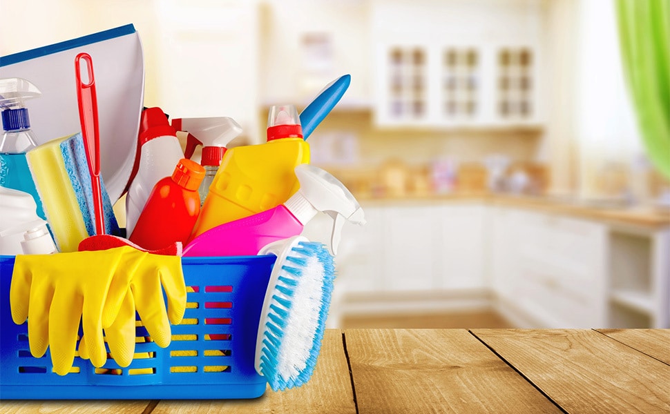 A basket of cleaning supplies sitting on a kitchen table.