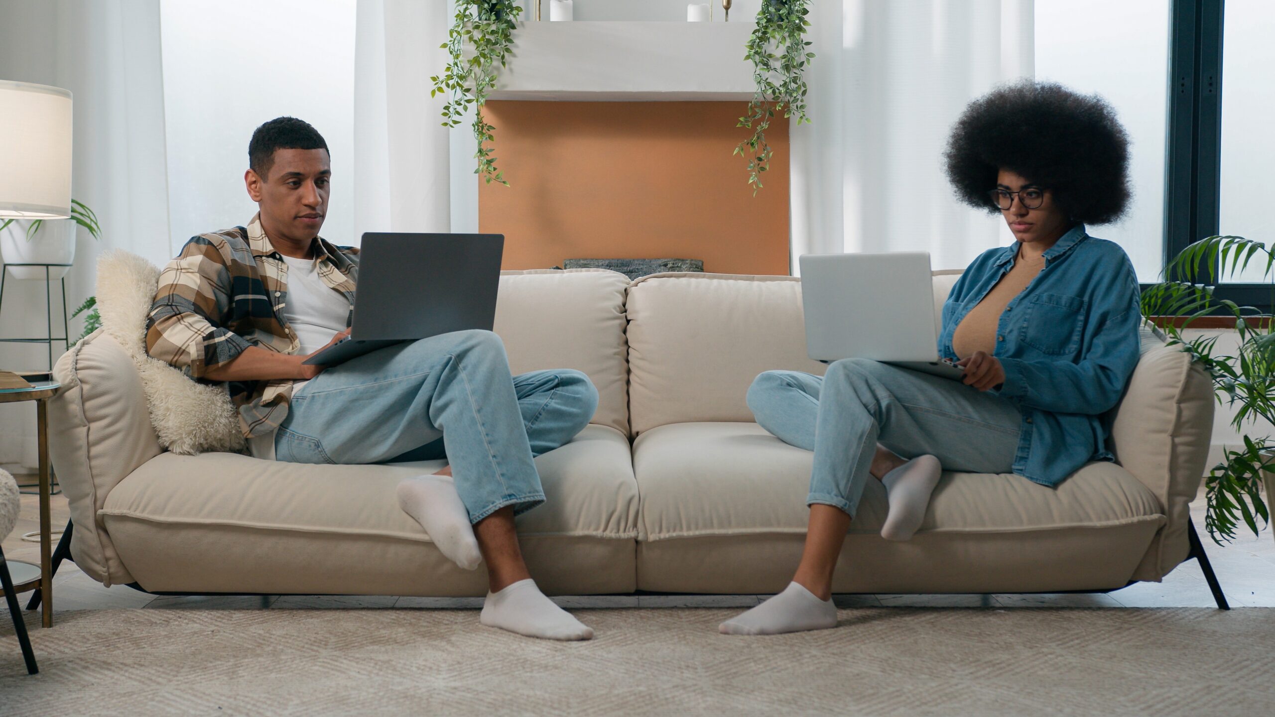 couple relaxing and working on laptops at home because their weekly cleaning service is done
